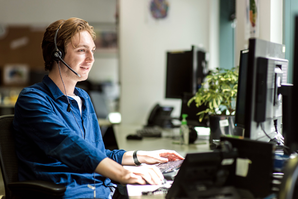 A phone counsellor sitting at a desk wearing a headset